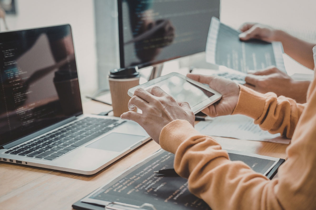 Team reviewing devices and technical documents during site readiness planning for a multi-location IT rollout