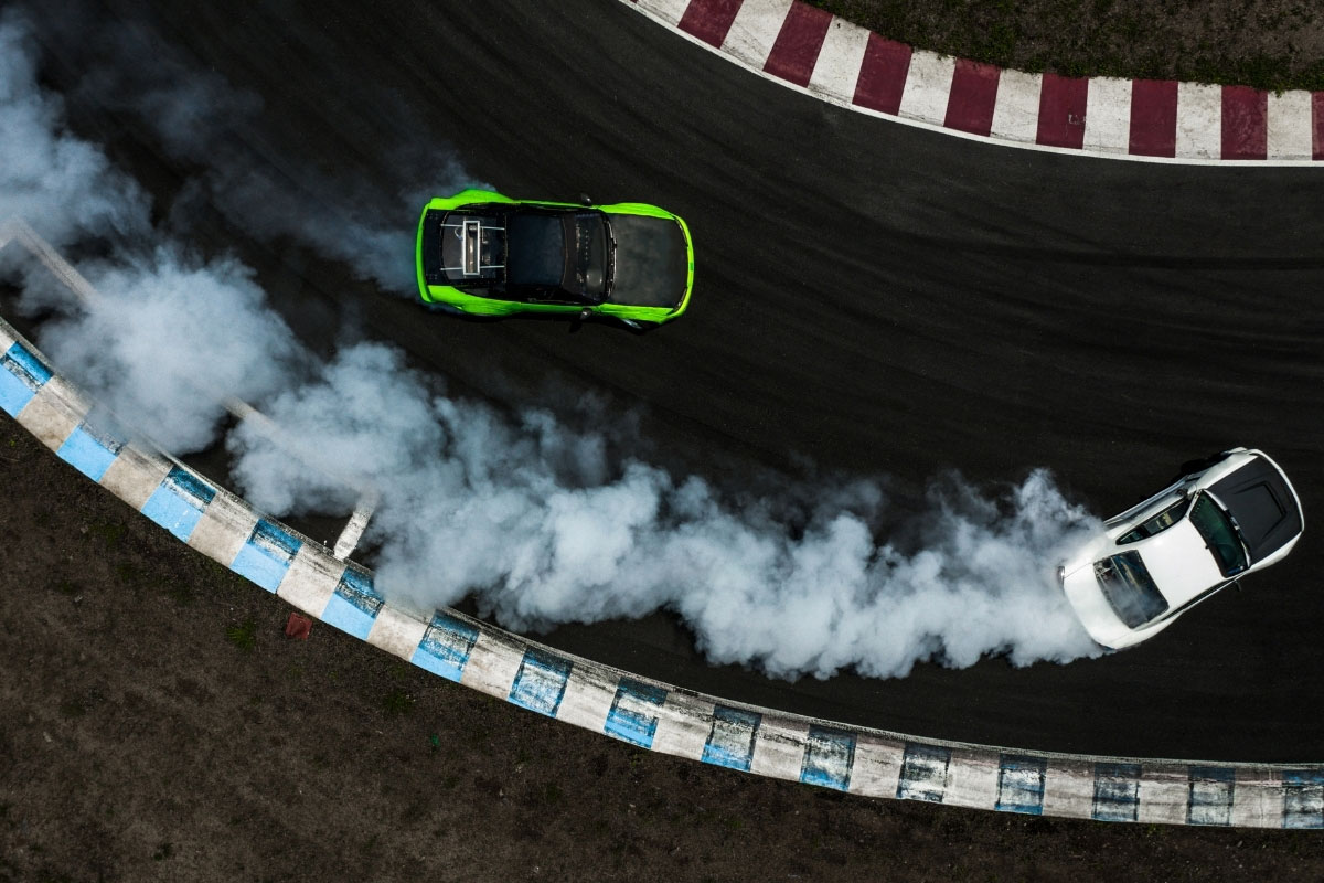 Image showing two cars drifting on a racetrack mirroring technology environments drifting apart without centralized IT controls