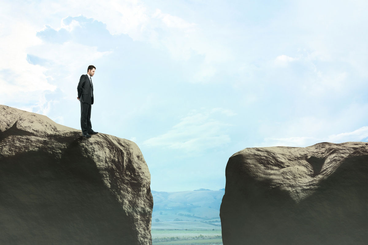 Executive standing at the edge of a rocky cliff representing the divide in IT post-acquisition strategy.