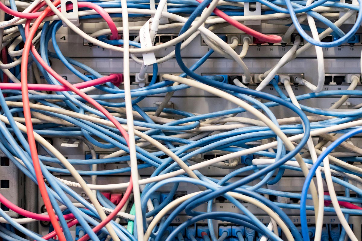 A disorganized server rack with tangled, messy ethernet cables, representing the "before" state of an IT closet remediation project