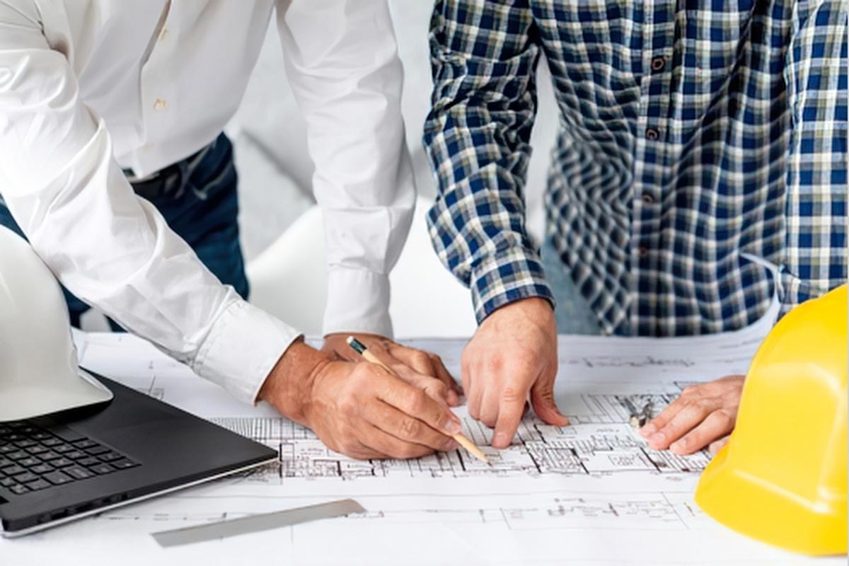 Two professionals reviewing technical blueprints and site plans for an IT rollout, representing strategic partnership and operational planning.